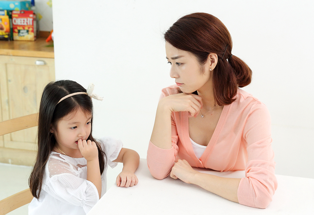 손톱 뜯는 아이와 아이를 바라보며 걱정하는 엄마