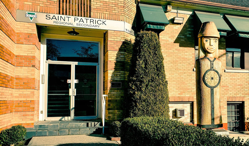 A photo of St. Patrick Regional Secondary School with a totem pole.
