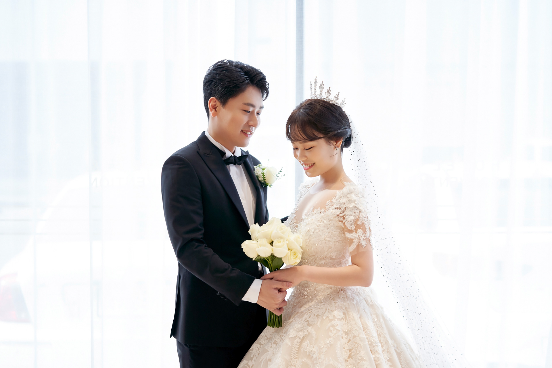 밝은 창을 등지고 부케를 함께 든 신랑신부
