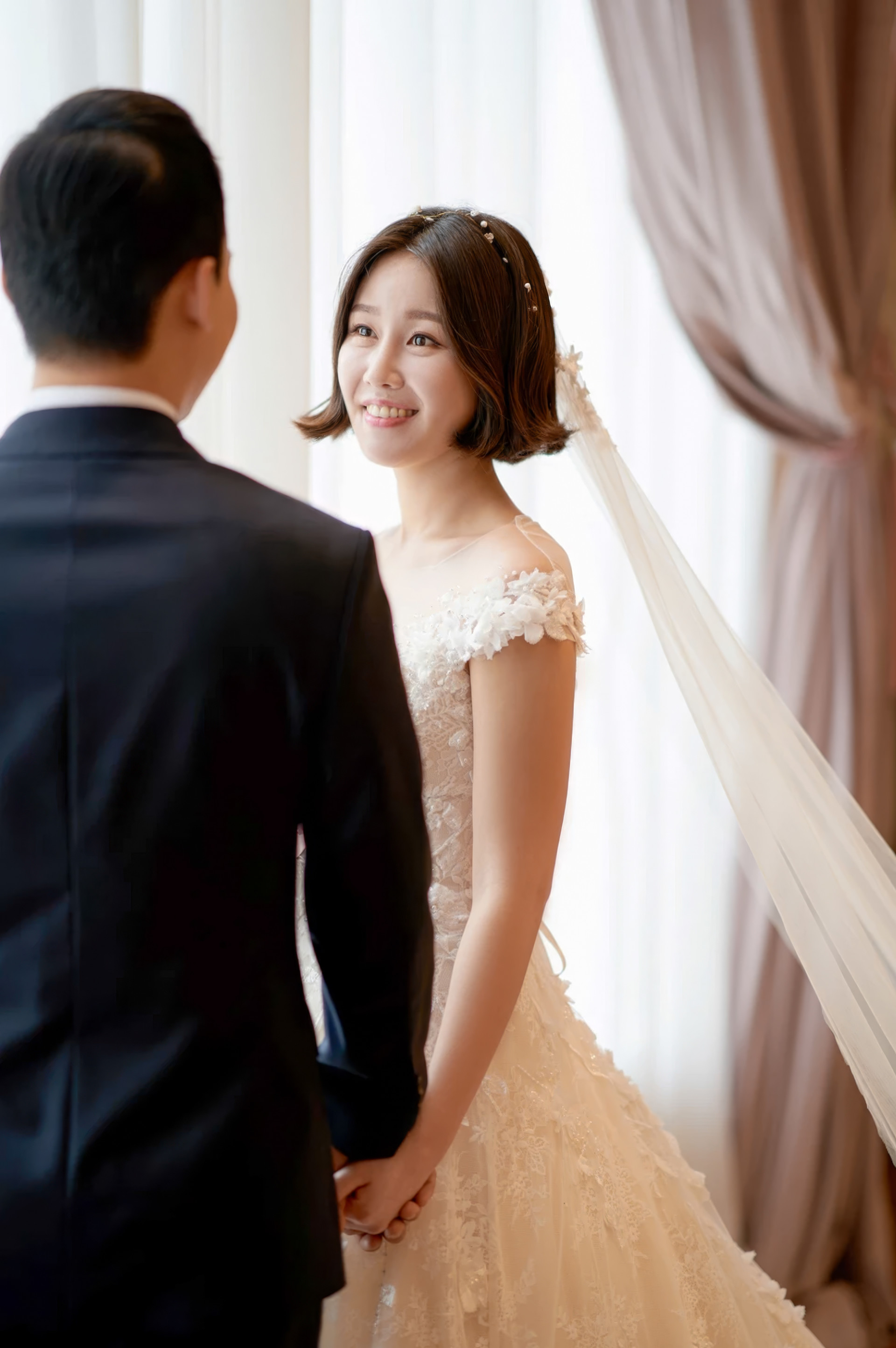 꽃잎이 날리는 버진로드를 팔짱 끼고 걸어 나오는 신랑신부, 천장에 샹들리에가 걸려 있다