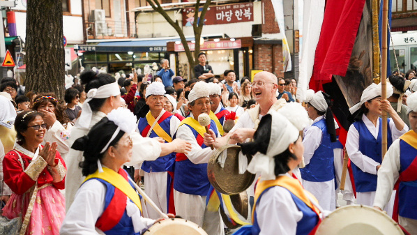 "전주한옥마을 전통연희 퍼레이드에서 외국인 관객이 징을 치며 공연에 참여하는 모습"