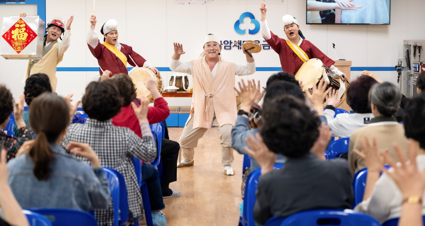 어르신들을 향해 신명나게 북을 치며 공연하는 연희자들, 함께 손을 들어 호응하는 관객들