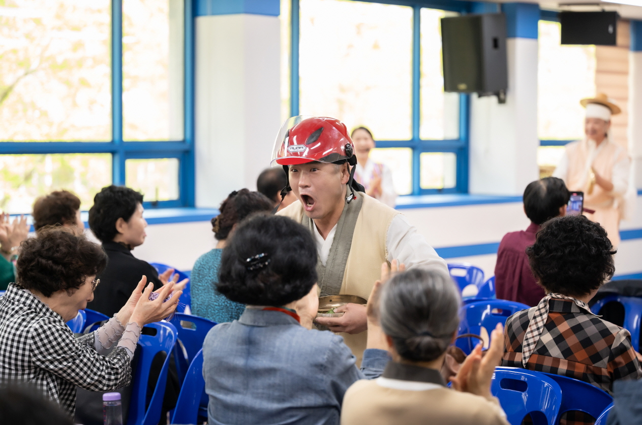 관객석으로 다가온 연희자가 헬멧을 쓰고 코믹하게 등장해 어르신들에게 웃음을 주는 장면