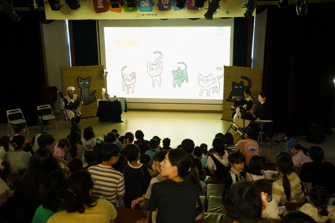 순천 기적의도서관에서 열린 어린이 공연 ‘나는 고양이로소이다’를 관람 중인 관객들. 무대에는 고양이 그림이 비춰지고, 전통 악기를 연주하는 출연진이 양쪽에 위치해 있다.
