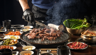 불판에 갈비를 구워 다양한 반찬을 곁들인 푸짐한 상차림