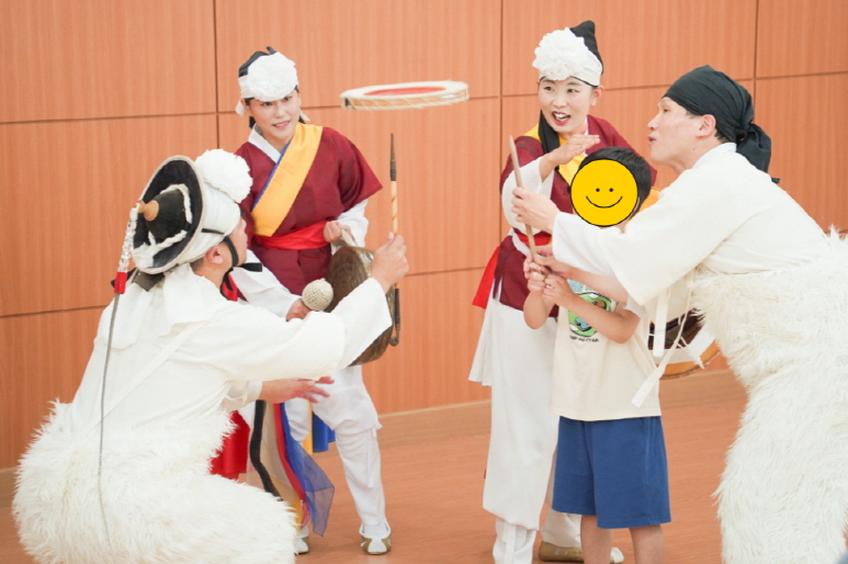 풍물마당놀이 해피 교육 공연 – 연희자와 아이가 함께 버나놀이(접시돌리기)를 체험하며 웃음과 전통을 배우는 장면