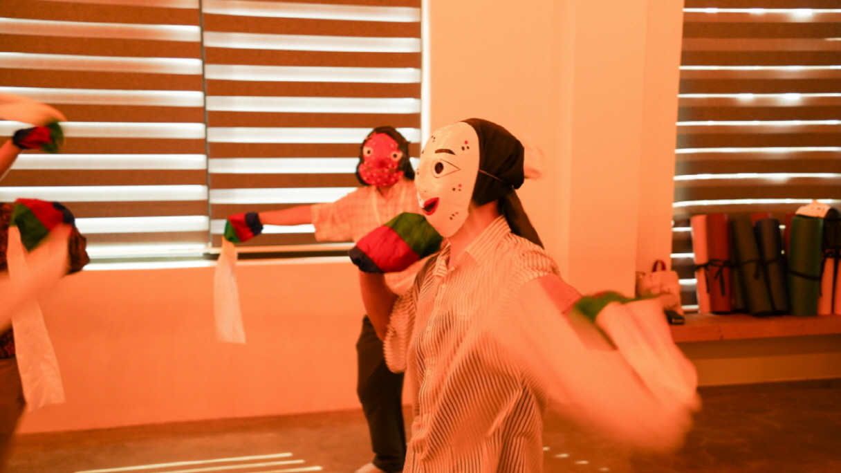 한바탕 얼쑤 체험에서 탈을 쓰고 오방색 천을 흔들며 전통 탈춤을 체험하는 외국인 참가자들