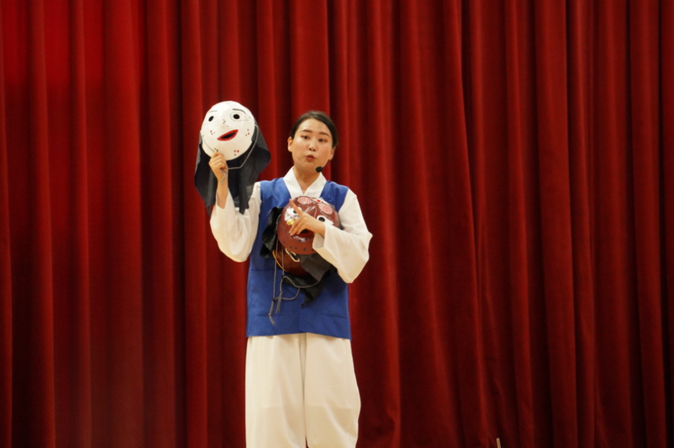 초등학교 K-POP 탈춤체험 강사 – 무대에서 전통 탈을 들고 설명하는 모습