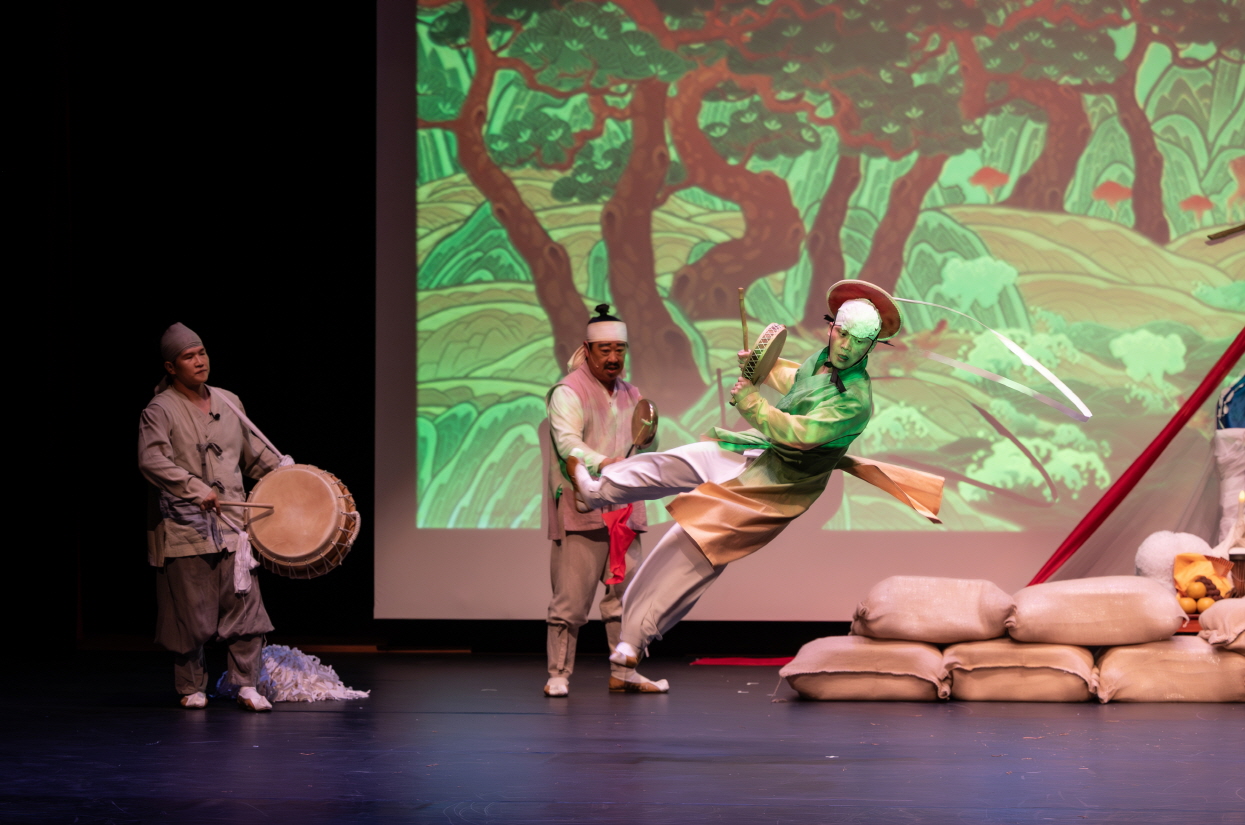 출연자가 공중에 점프하며 소고춤을 추는 장면, 역동적인 몸짓과 에너지가 전해지는 마당놀이 지신지신 공연 무대 장면