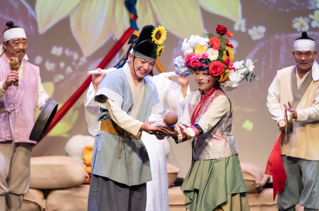 화려한 꽃장식 모자를 쓴 신부와 해바라기 모자를 쓴 신랑이 아기를 함께 안아주는 장면, 출연자들이 축하를 해준다. 마당놀이 지신지신의 유쾌하고 따뜻한 분위기