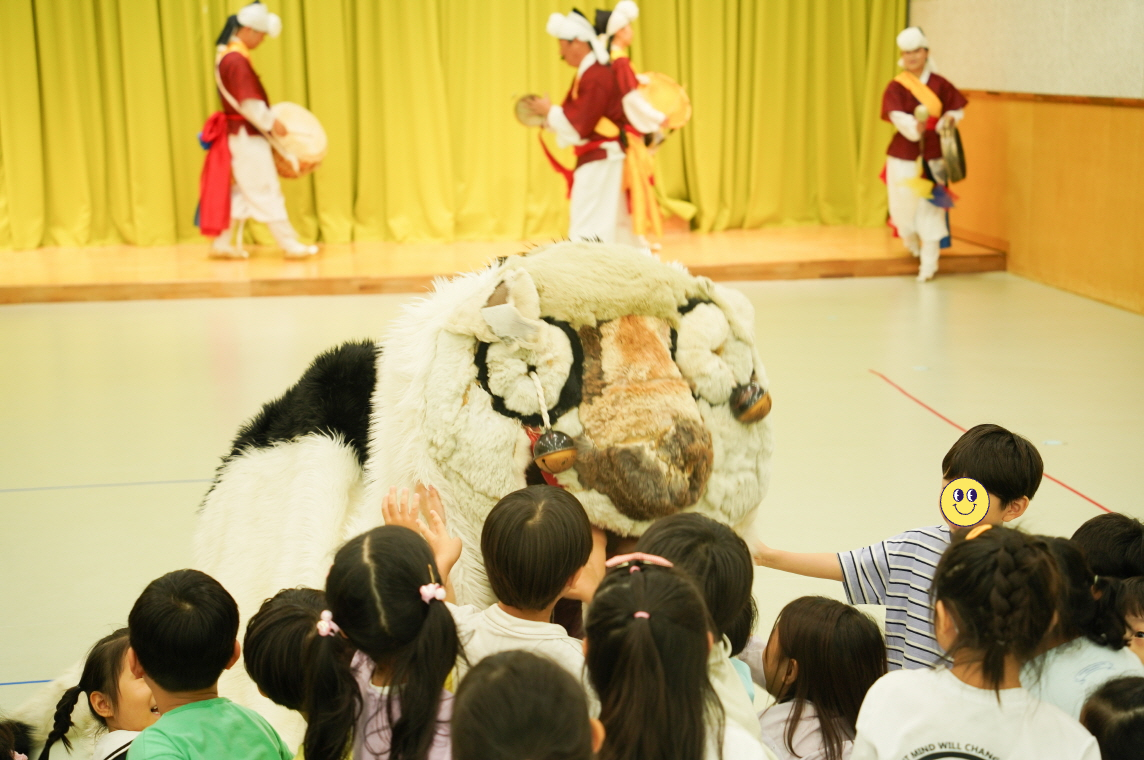 전주아름유치원에서 열린 유치원 공연 ‘풍물마당놀이 해피’ 중, 강아지 탈을 쓴 해피가 아이들 앞으로 몸을 낮추며 다가오자 아이들이 손을 뻗어 쓰다듬으며 교감하고 있는 모습