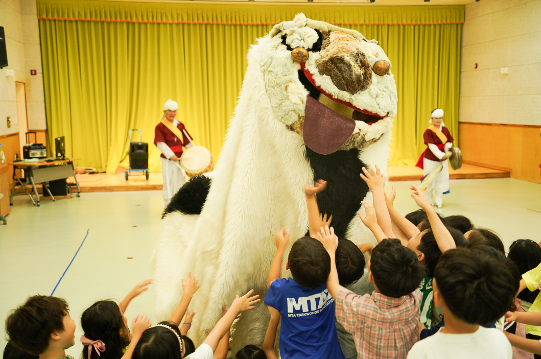 전주아름유치원에서 열린 유치원 공연 ‘풍물마당놀이 해피’ 중, 커다란 강아지 탈을 쓴 해피가 아이들 앞으로 다가오자 아이들이 손을 뻗으며 즐겁게 맞이하고 있는 모습