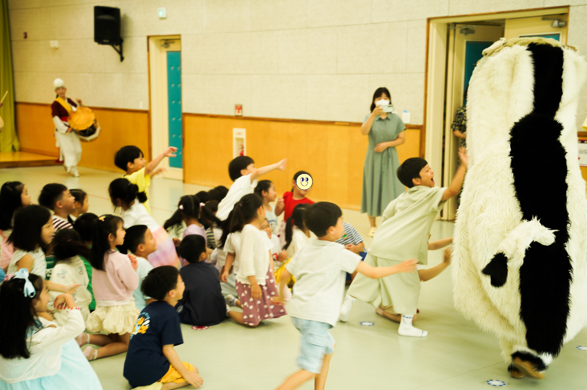 전주아름유치원에서 열린 유치원 공연 ‘풍물마당놀이 해피’ 중, 강아지 탈을 쓴 해피가 아이들 앞에서 도망치듯 달아나고 아이들이 즐겁게 쫓아가며 손을 뻗는 모습