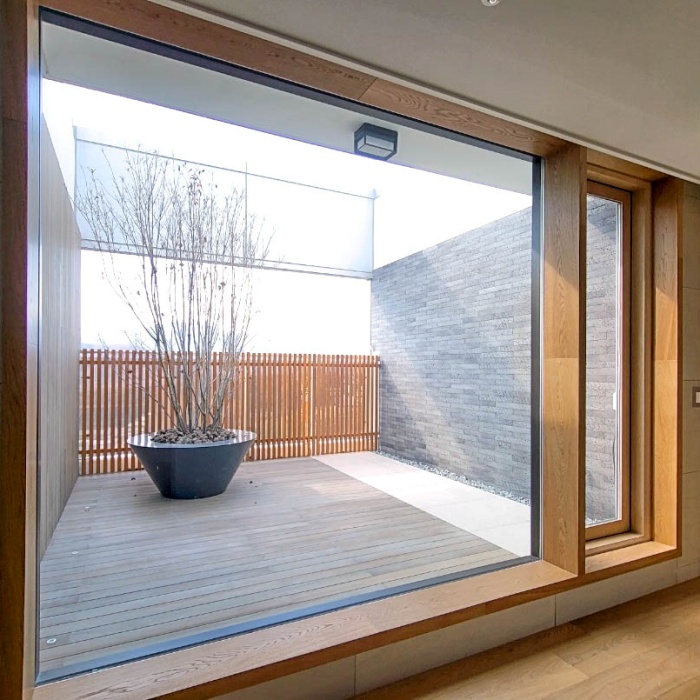 테라스 창과 연결된 대형 원목 윈도우 시트 – 오크 프레임 마감