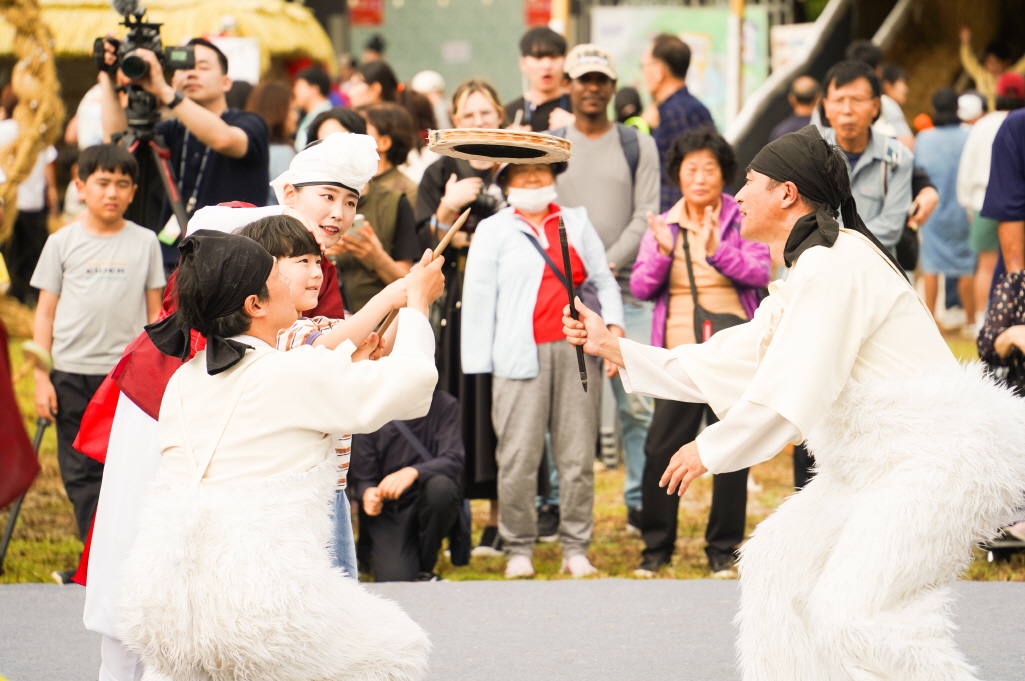 2025 안성 바우덕이 축제 풍물마당놀이 해피 공연에서 어린이와 출연자가 함께 버나놀이 접시돌리기 묘기를 배우며 즐겁게 참여하는 장면