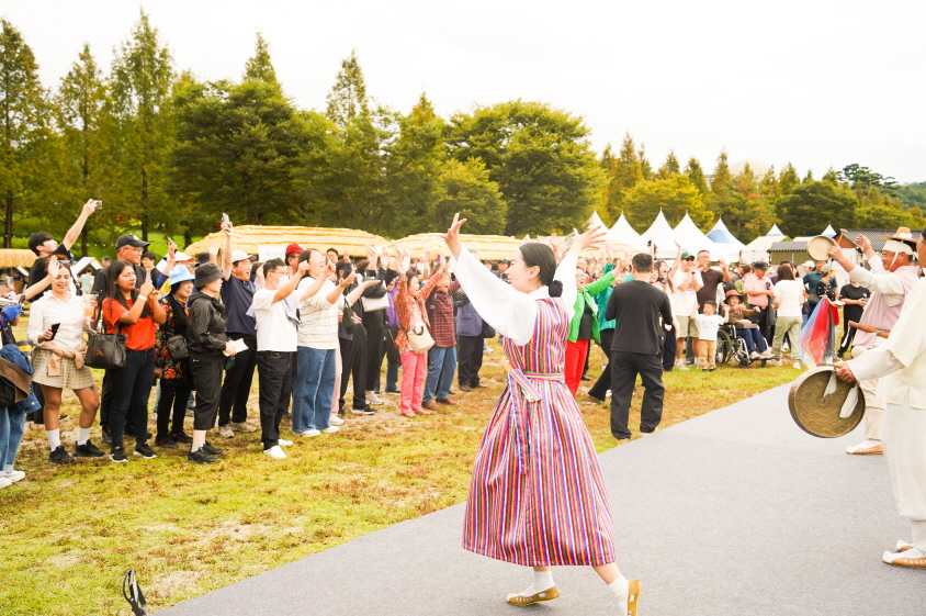 안성 바우덕이 축제에서 진행된 전통 마당놀이 복이팡팡 공연 현장, 출연자와 관객이 함께 손을 들며 흥겨운 풍물놀이를 즐기고 있는 모습