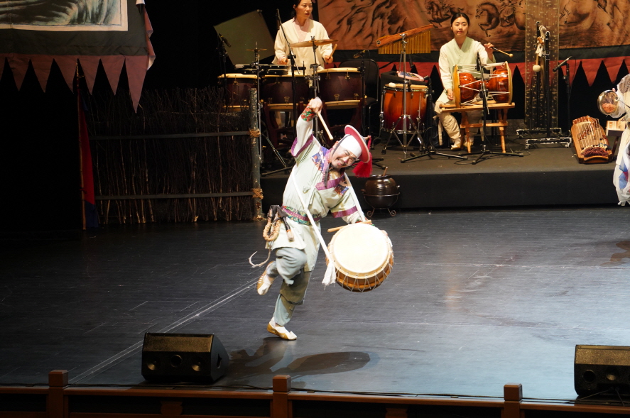 마당놀이 용을쫓는사냥꾼 공연에서 상모를 쓴 연희자가 북을 메고 역동적인 춤과 연주를 선보이는 장면