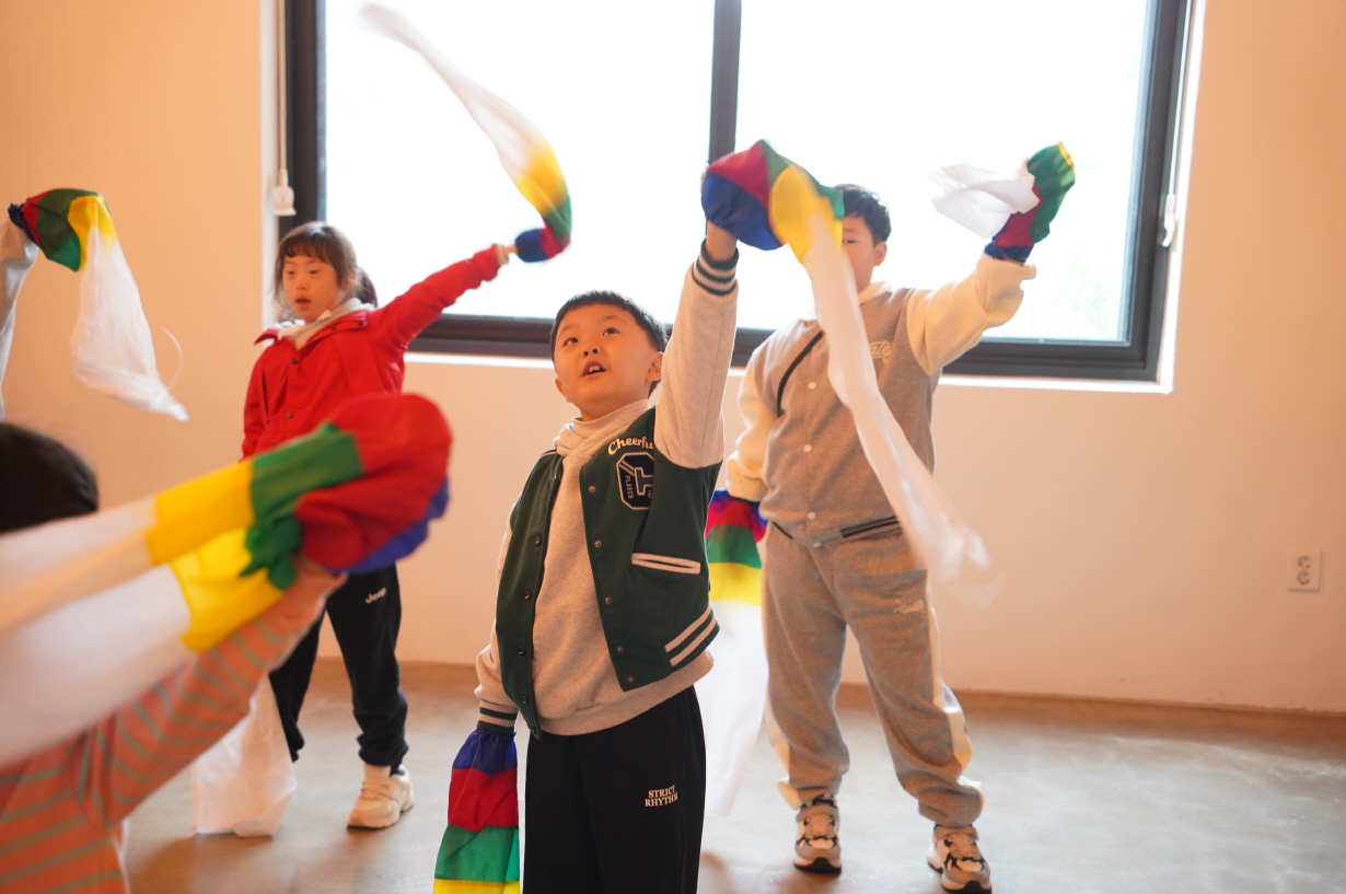 주한옥마을 승암어울마당에서 초등학생들이 오색 수건을 들고 소고 장단에 맞춰 팔을 들어 올리며 춤 동작을 배우는 한바탕 얼쑤 전통체험 장면