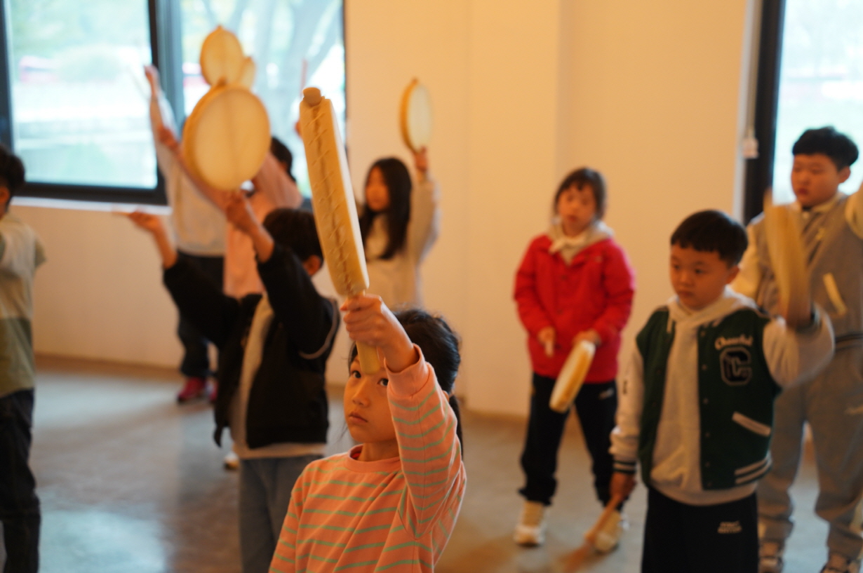 전주한옥마을 승암어울마당에서 초등학생들이 소고를 들고 전통 장단에 맞춰 팔을 들어 올리며 리듬 동작을 배우는 한바탕 얼쑤 체험 장면