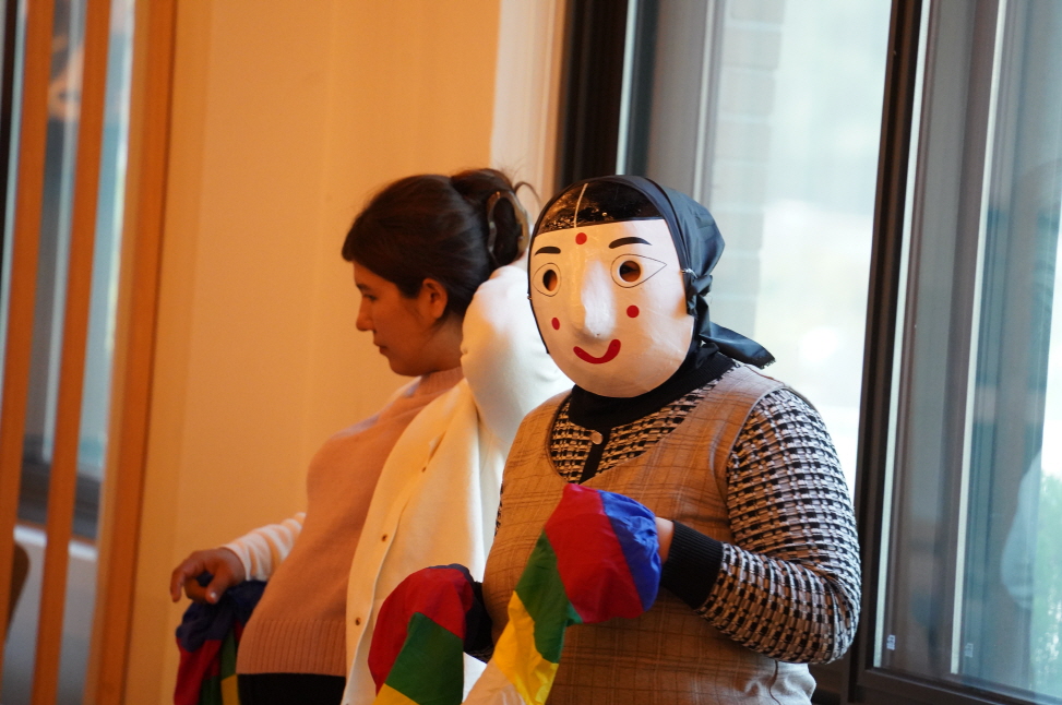 전통탈을 쓴 외국인들이 함께 어깨를 들썩이며 한국의 탈춤을 체험하는 활기찬 분위기의 전주한옥마을 체험 장면