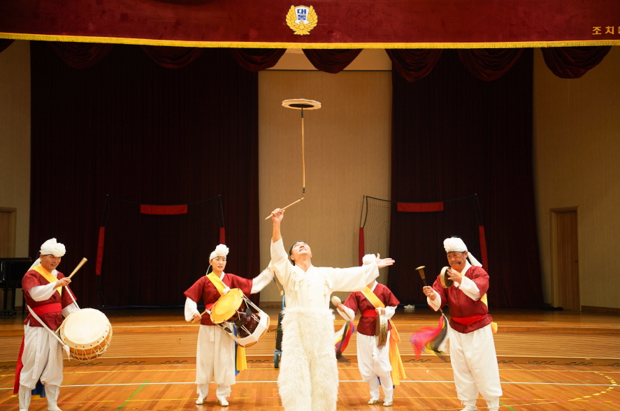 풍물마당놀이 해피 공연에서 출연자가 버나놀이(접시돌리기) 묘기를 선보이며 장단을 맞추는 풍물단의 모습｜조치원 대동병설유치원 전통공연