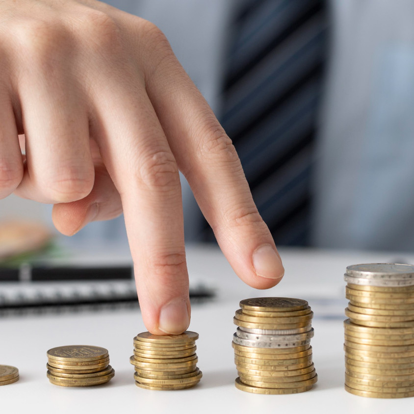 <alt=손가락이 동전 더미를 가리키는 모습>