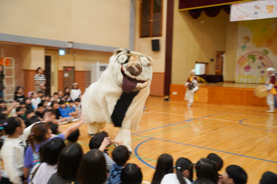 풍물마당놀이 해피 공연에서 아이들이 커다란 강아지탈 해피를 향해 손을 흔들며 즐거워하는 모습