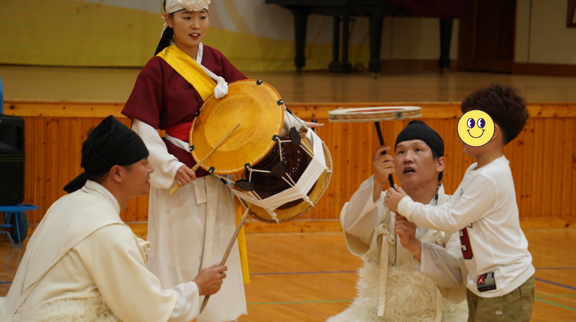 “풍물마당놀이 해피 공연에서 연희자가 어린이와 함께 버나(접시돌리기) 체험을 진행하며 즐겁게 소통하는 모습