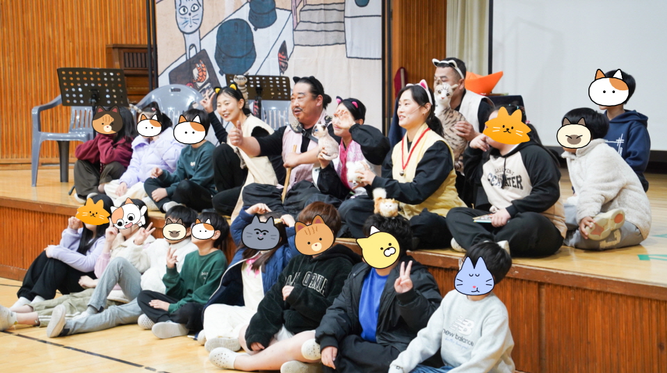 어린이 마당놀이 ‘나는 고양이로소이다’ 공연 종료 후 광주 오치초등학교 학생들과 배우들이 무대 앞에서 함께 기념촬영하는 모습 — 학생들은 프라이버시 보호를 위해 얼굴이 고양이 그래픽으로 가려져 있음