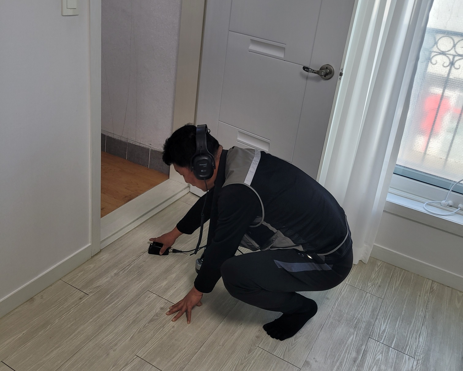 부천 원미구 아파트 거실 바닥에서 청음식 누수탐지기로 누수 지점을 검사하는 모습