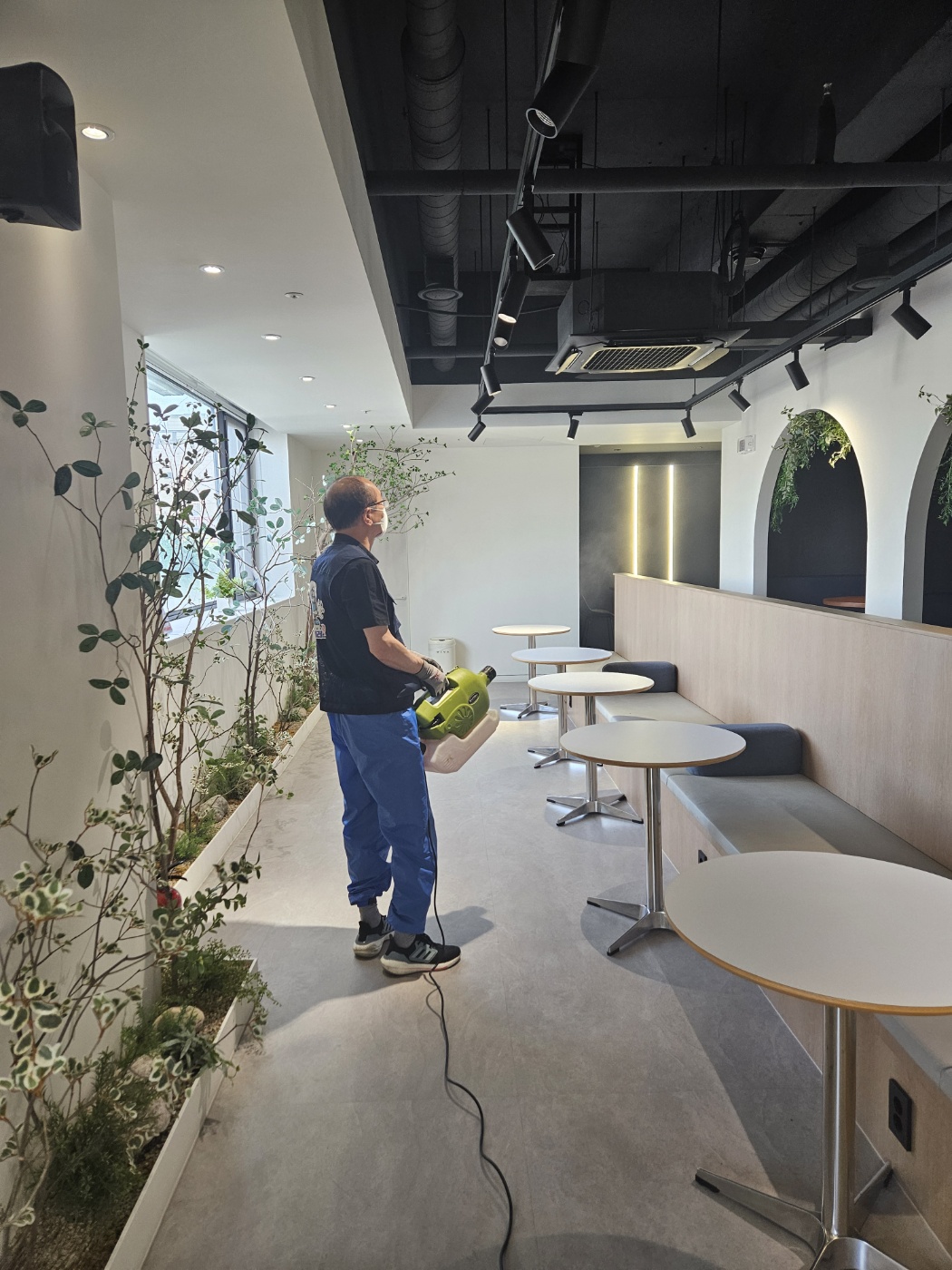 상업 공간인 카페 내부를 해충 방역하는 작업자