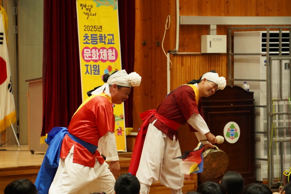 사물놀이 연희자들이 몸짓과 연기로 아이들의 박수장단 사물놀이를 진행하는 초등학교 체험형 전통공연 장면