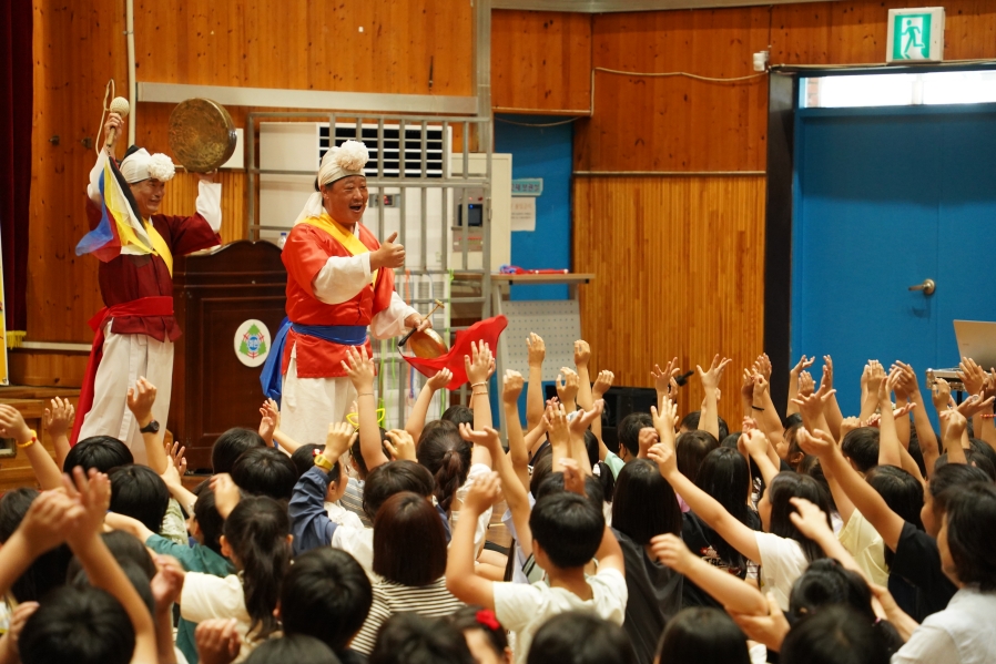 초등학생들이 손을 들고 박수로 함께 참여하며 사물놀이를 완성하는 체험형 전통공연 장면