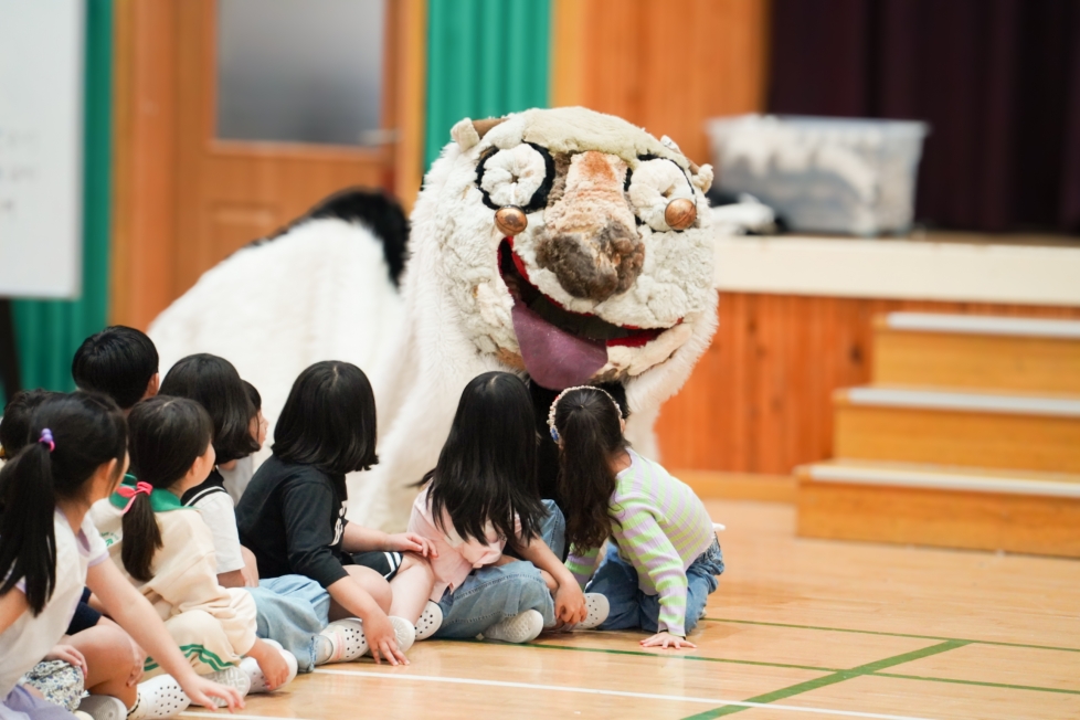 유치원 강당에서 강아지탈 해피가 아이들과 가까이 다가가 눈높이로 교감하는 체험형 전통공연 풍물마당놀이 해피 현장