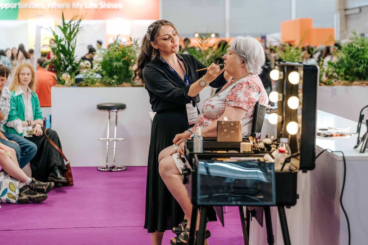 Démonstration de maquillage par des professionnels lors d'un atelier K-Class à la Korea Expo, encadrée par des miroirs de maquillage