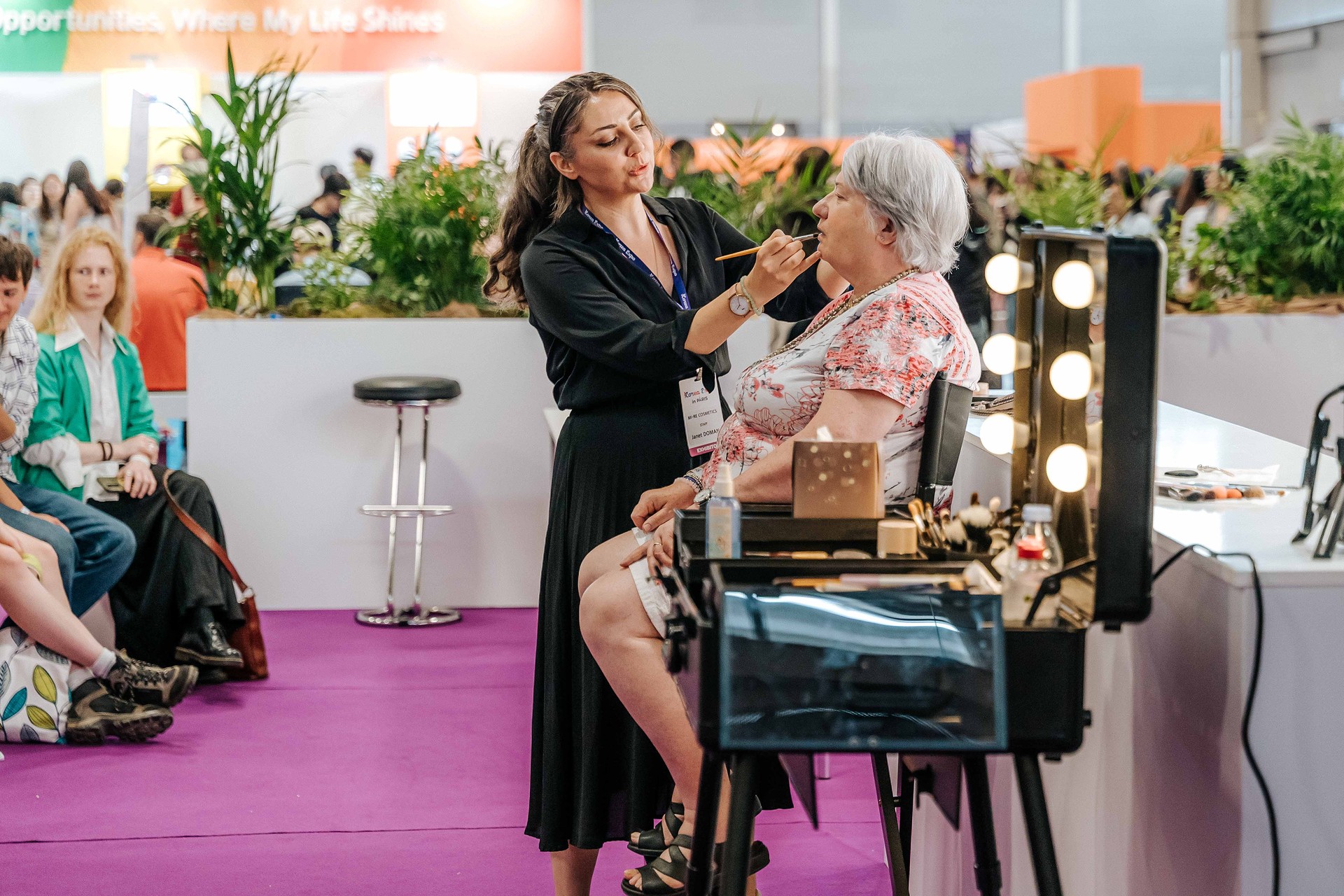 Makeup demonstration by professionals during a K-Class workshop at the Korea Expo, framed by makeup mirrors