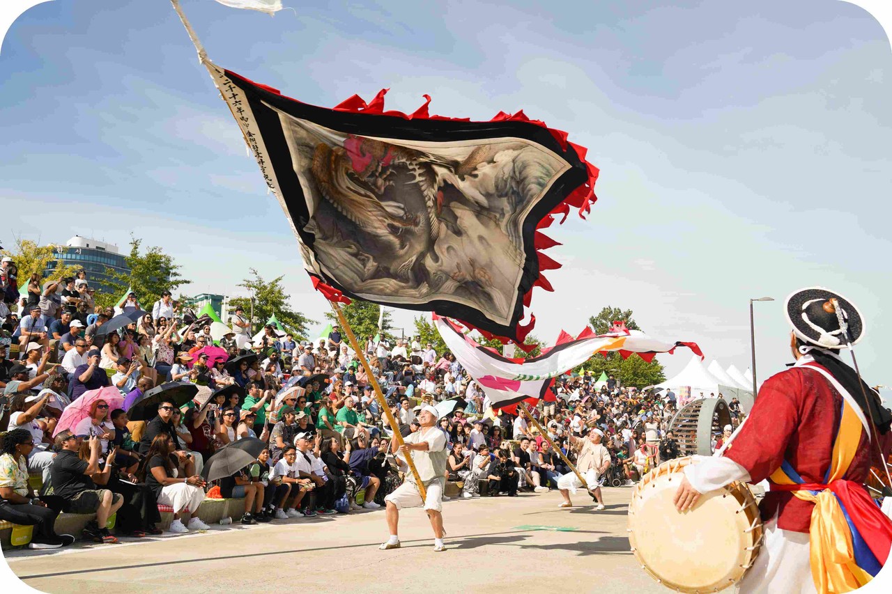 여의도 한강공원 수변무대 계단석을 가득 채운 외국인 관광객들에게 대형 용깃발 기예를 선보이며 한국 전통 공연의 매력을 전파하는 현장
