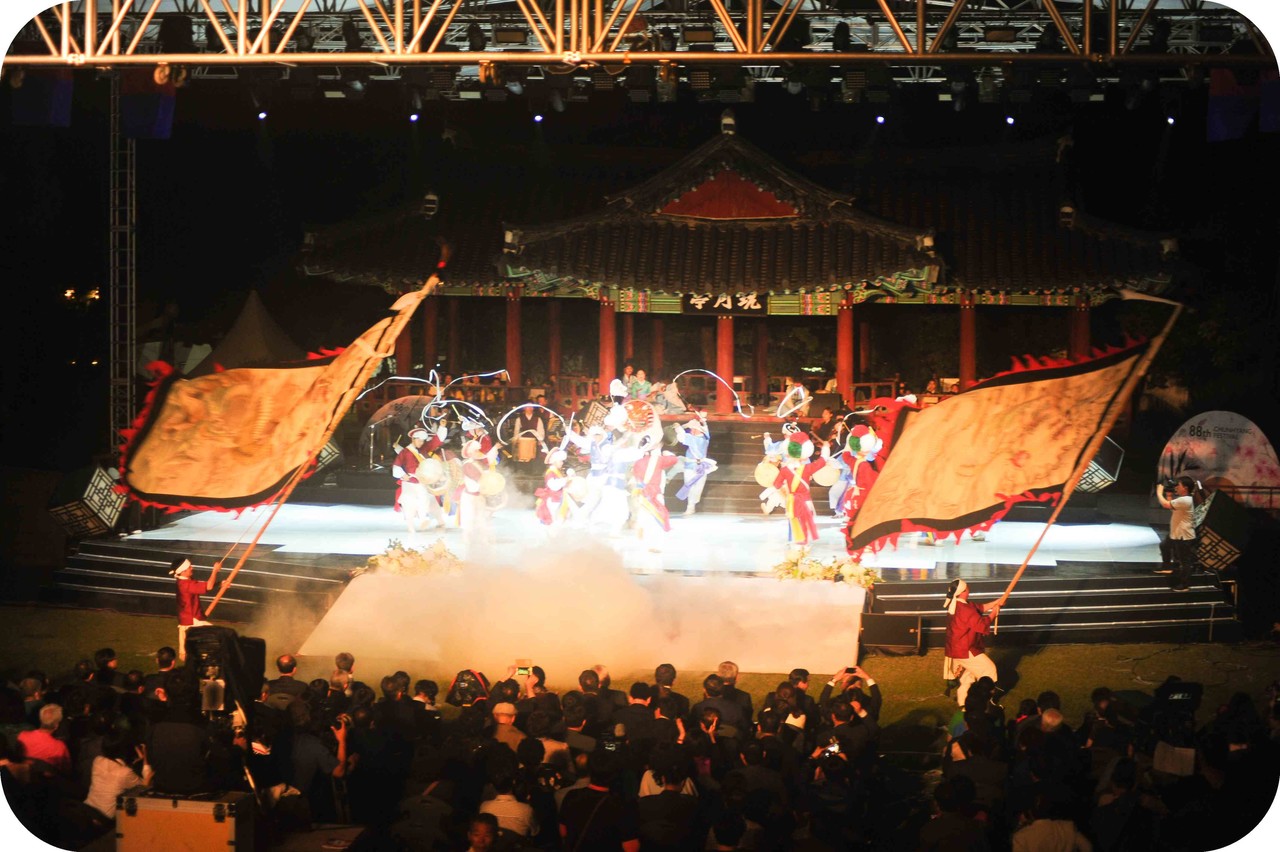 남원춘향제 개막공연 메인 무대에서 화려한 조명과 안개가 어우러진 가운데 펼쳐지는 웅장한 기접 퍼포먼스와 전통 연희팀의 화려한 군무