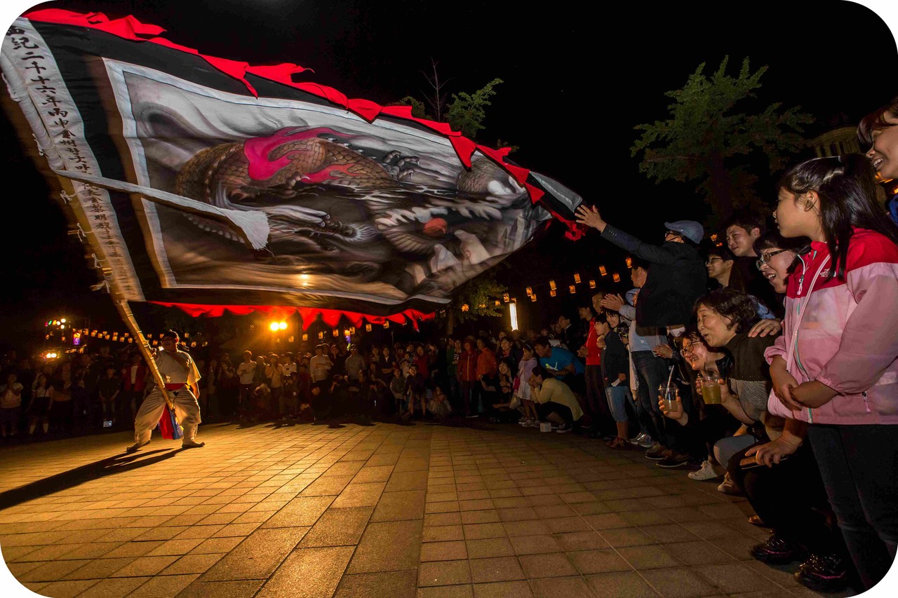 전주문화재야행 개막공연 중 어두운 밤하늘 아래 대형 용깃발이 관객석 코앞까지 낮게 비행하며 시민들과 초밀착 소통하는 생생한 참여형 공연 장면