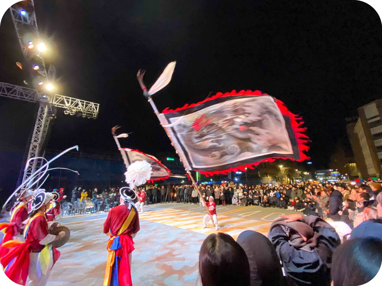 전주 제야의 종 타종식 축제 현장에서 화려한 야간 조명을 받으며 하늘 높이 솟구친 대형 용깃발과 이를 지켜보는 수많은 운집 인파의 열기