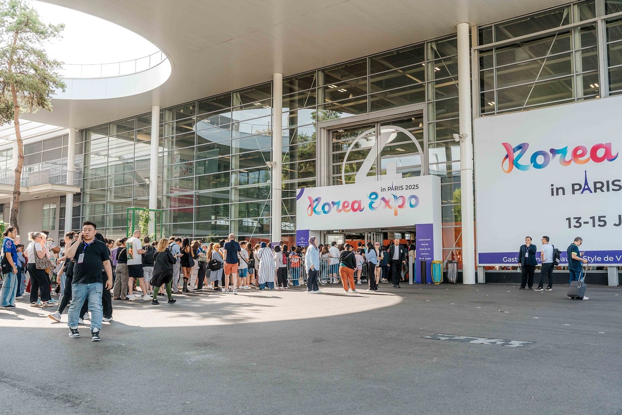 View of the main entrance of Pavilion 5 of the Korea Expo in Paris, with many visitors lining up to enter under a large event banner