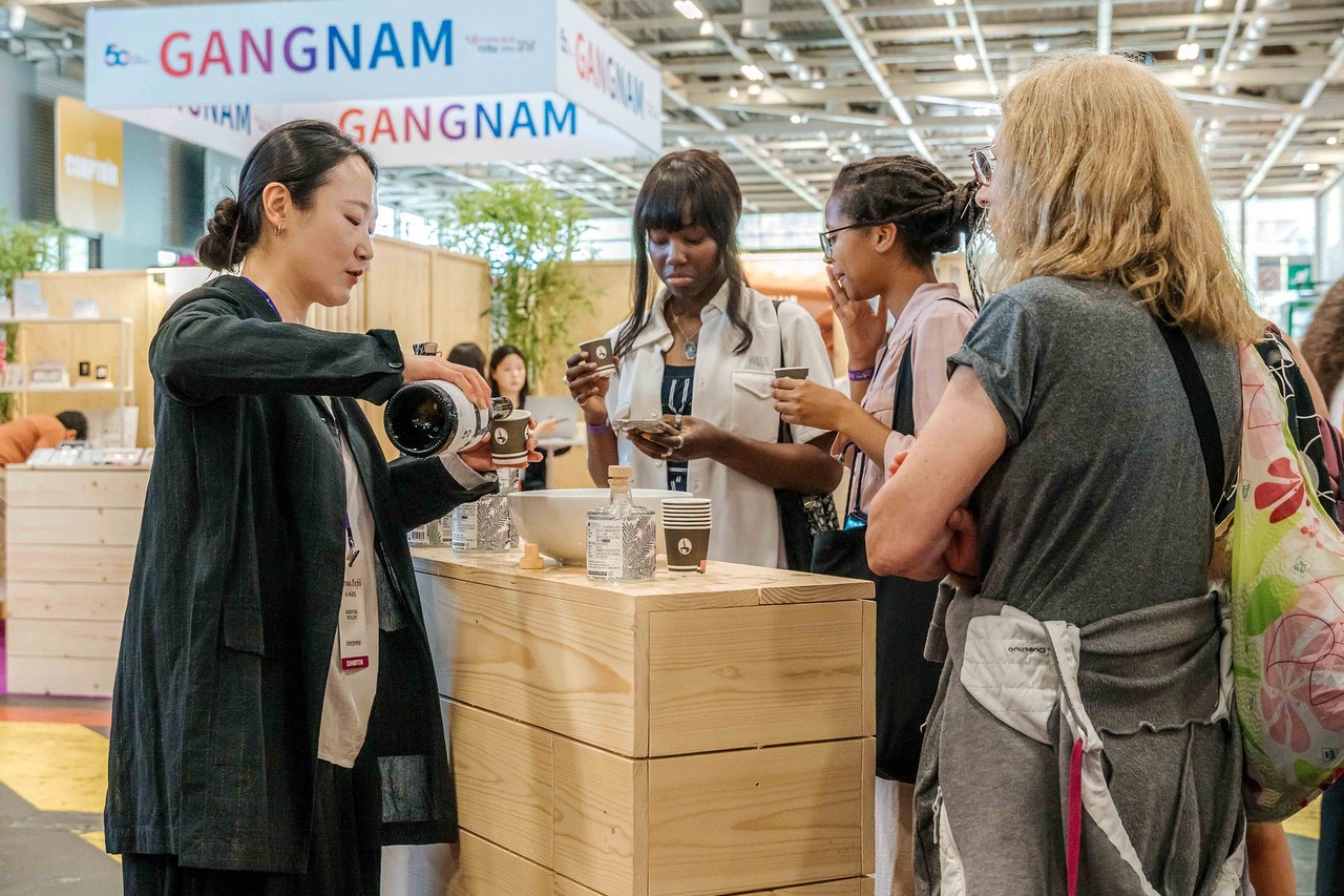 A B2B business meeting in a professional environment at the Korea Expo Paris, where a businessman and an exhibitor discuss Korean products, symbolizing the networking platform