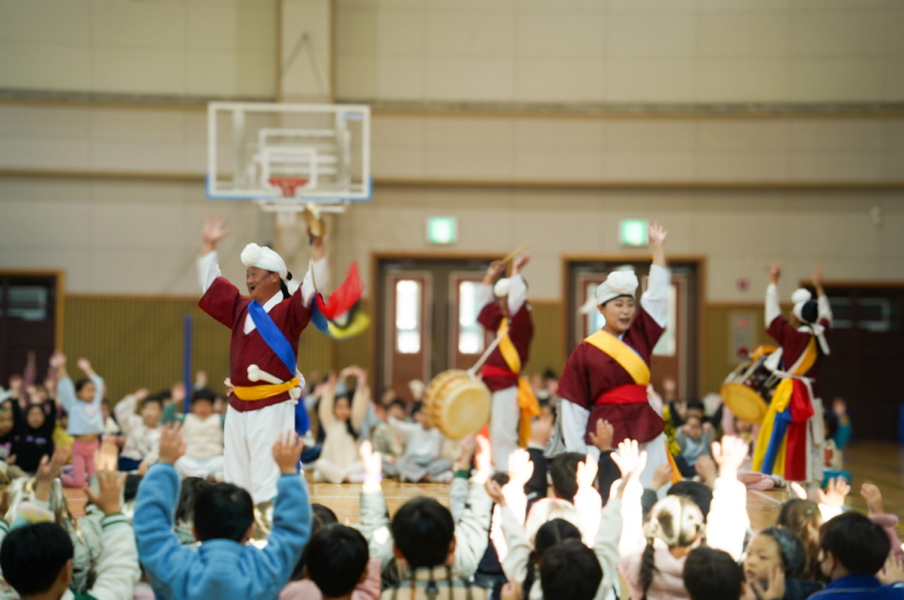 유치원 전통공연 ‘풍물마당놀이 해피’에서 연희자들이 장단을 치며 아이들과 함께 손을 들고 참여하는 모습