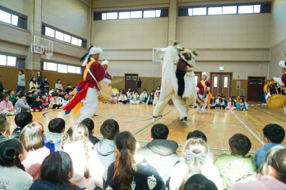 유치원 체육관에서 진행된 풍물마당놀이 해피 공연 전경, 해피와 연희자들이 아이들 둘러싸인 가운데 공연하는 장면