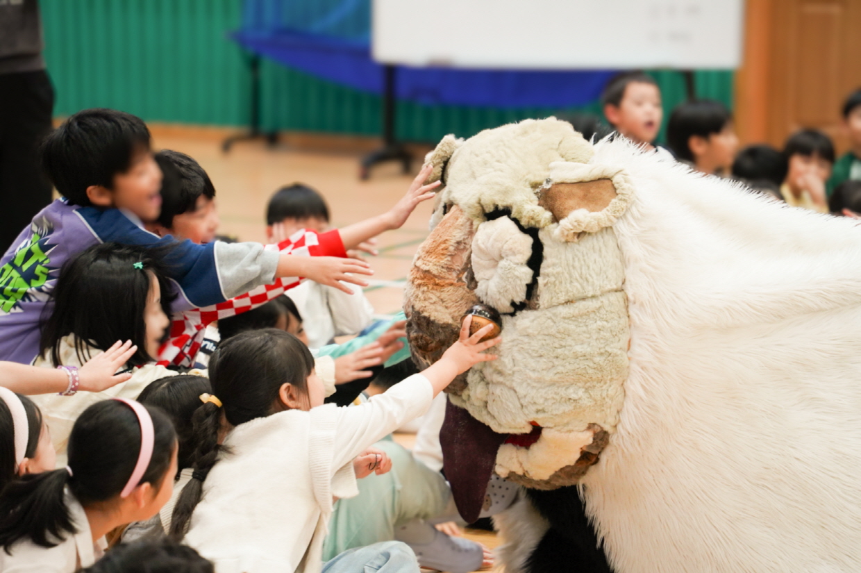 유치원 전통공연 풍물마당놀이 해피에서 아이들이 강아지 탈 해피를 만지며 즐거워하는 장면