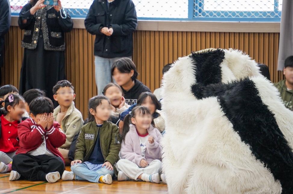 광주 비아초 병설유치원 강당에서 아이들이 풍물마당놀이 공연 중 등장한 커다란 강아지 해피를 보고 놀라 얼굴을 가리거나 환하게 웃으며 집중하는 모습