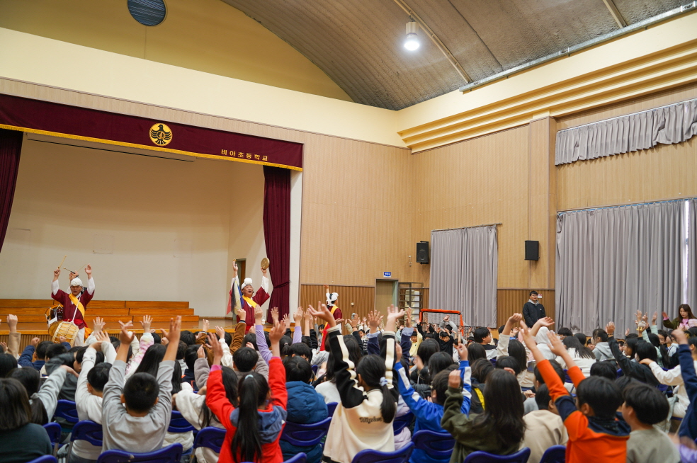 광주 비아초등학교 강당에서 합굿마을 단원들의 풍물 연주에 맞춰 전교생이 일제히 두 손을 번쩍 들고 신나게 노동요를 떼창하며 축제 같은 분위기를 즐기는 모습