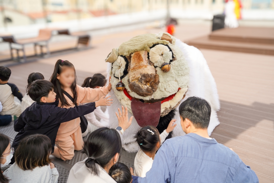 울산 강동바다도서관 풍물마당놀이 해피 공연에서 아이들이 강아지탈 캐릭터 해피를 직접 만지며 교감하는 장면