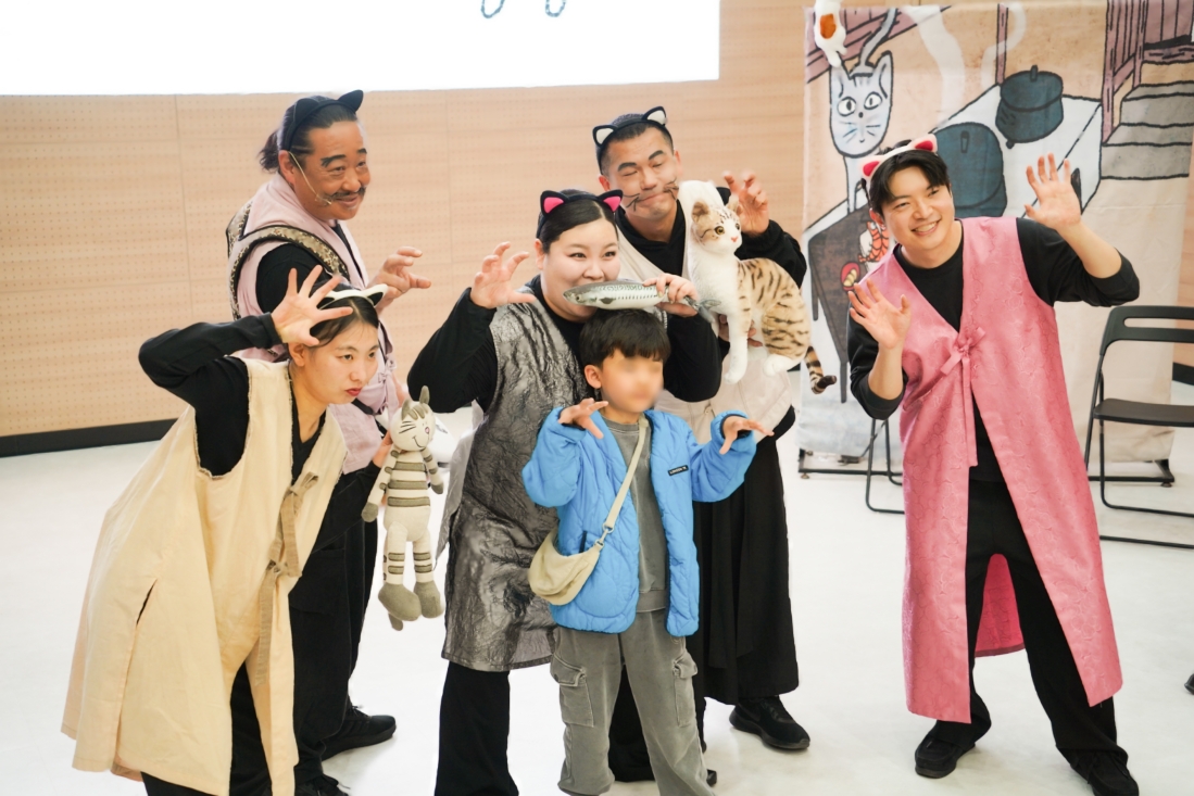 나는고양이로소이다 공연 후 배우 5인과 어린이 관객 포토타임 – 고양이 귀를 달고 생선·고양이 인형 소품을 들고 함께 포즈를 취하는 모습, 합굿마을