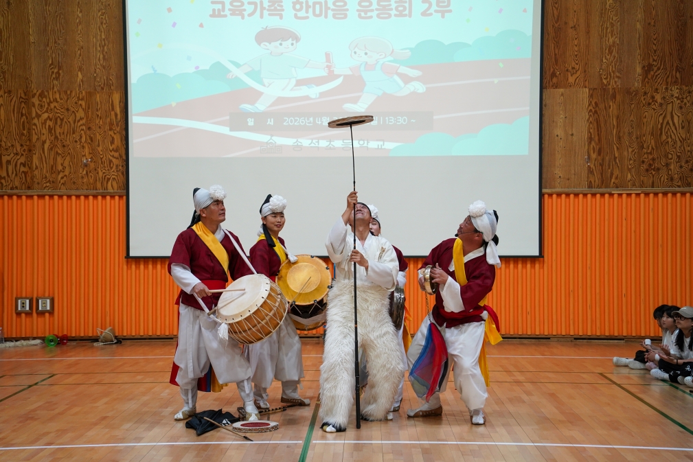 풍물단원이 장대 끝에 버나 접시를 올리고 있다